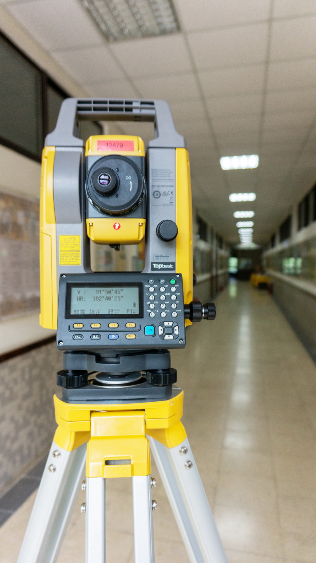 A surveying instrument (total station) placed on the indoor floor, used for civil engineering measurements